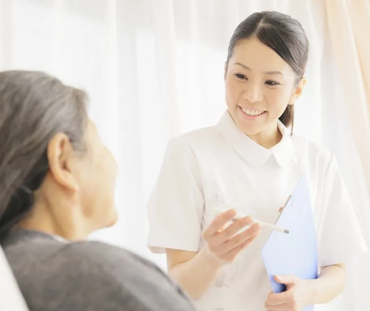 高齢の患者さんに笑顔で話しかける看護師