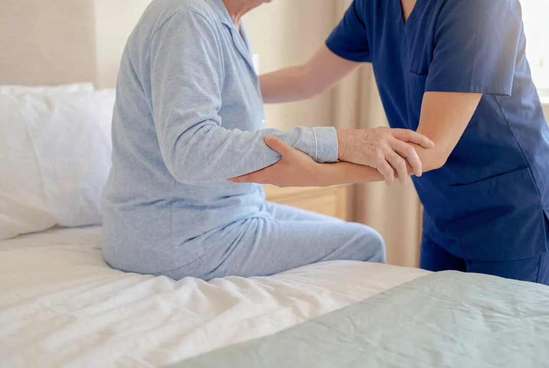 ベッドに腰かけた方の腕を支えるスタッフ